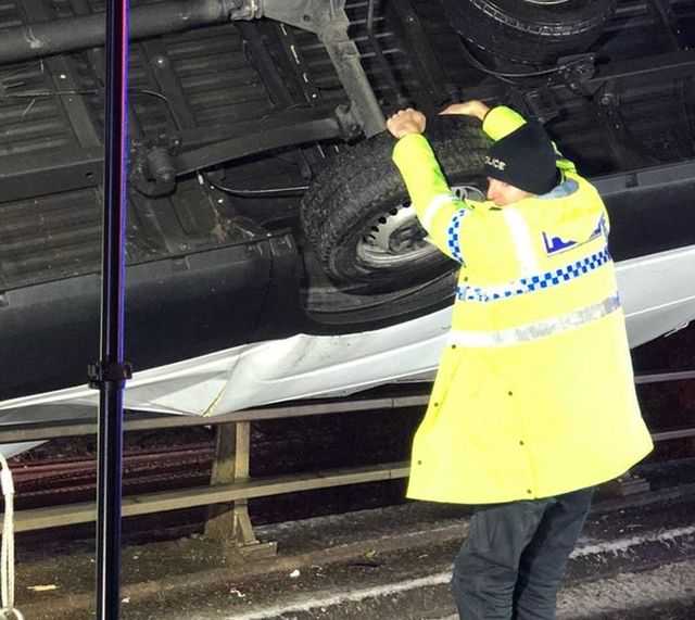 В Великобритании полицейский удерживал автомобиль, зависший на краю моста (2 фото)